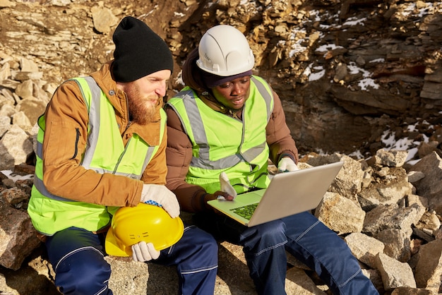 A diverse team of rescue workers using AI-powered software on laptops to analyze real-time satellite imagery in a disaster-stricken zone. The software highlights areas of highest risk and potential survivors, aiding in targeted rescue missions.  The atmosphere is tense but focused, with individuals collaborating closely.