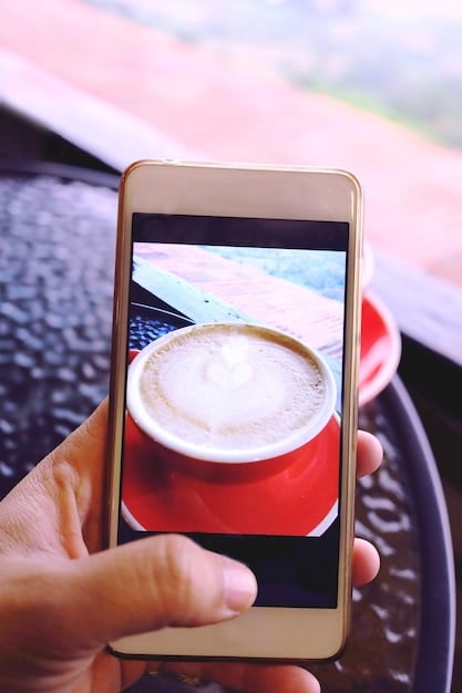 A close-up shot of a smartphone screen displaying a personalized advertisement for a local coffee shop. The ad features the user's name and showcases a specific menu item they frequently order. The background includes a blurred image of people enjoying coffee in a relaxed atmosphere.